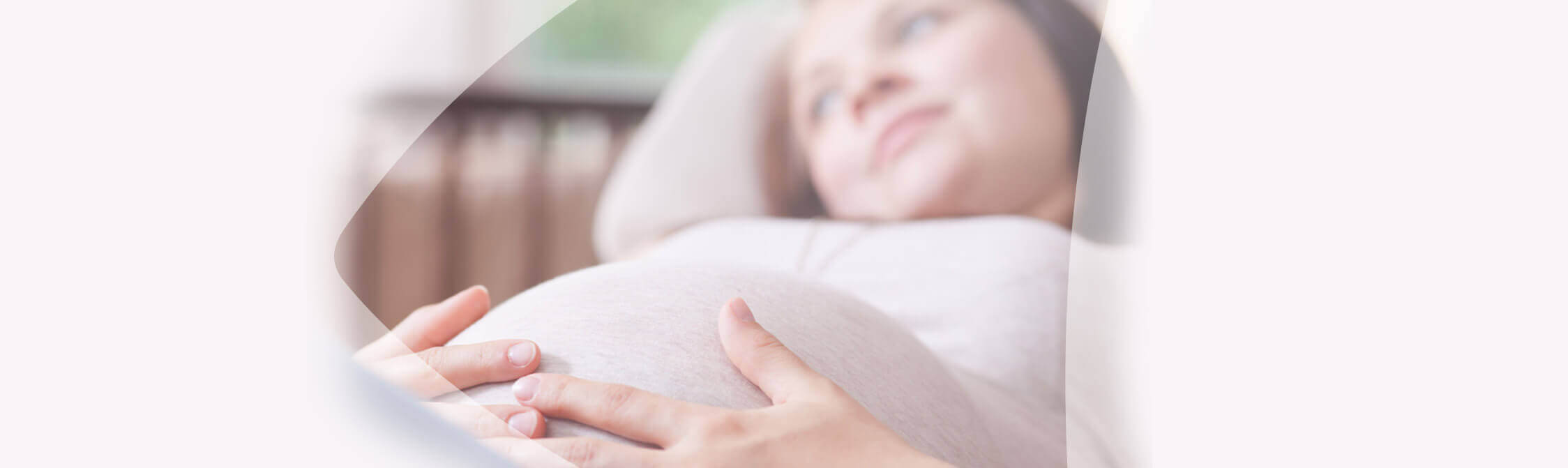 Une femme enceinte est couchée sur une canapé et tient son ventre