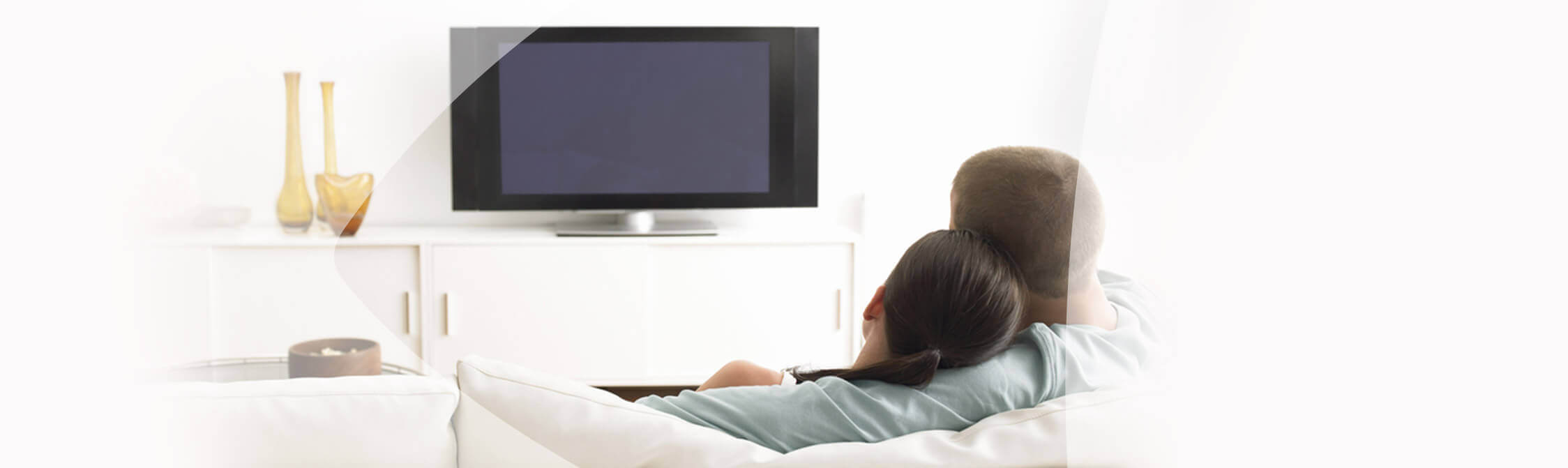 Un couple assis sur un canapé regarde la télévision